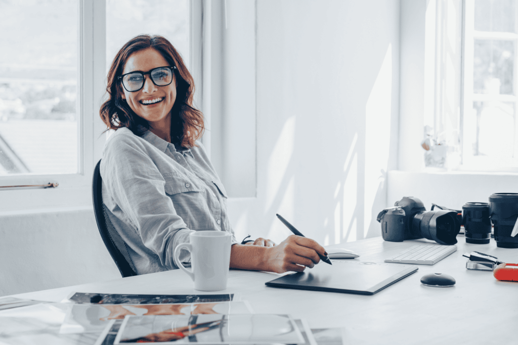 A happy woman at her desk learning about Good vs bad LinkedIn photos