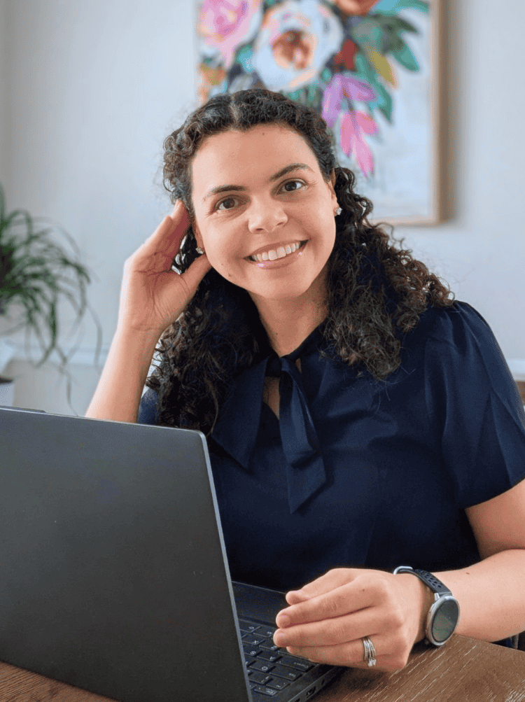 A woman smiling at her desk researching how to look for jobs while employed - Ana Goehner