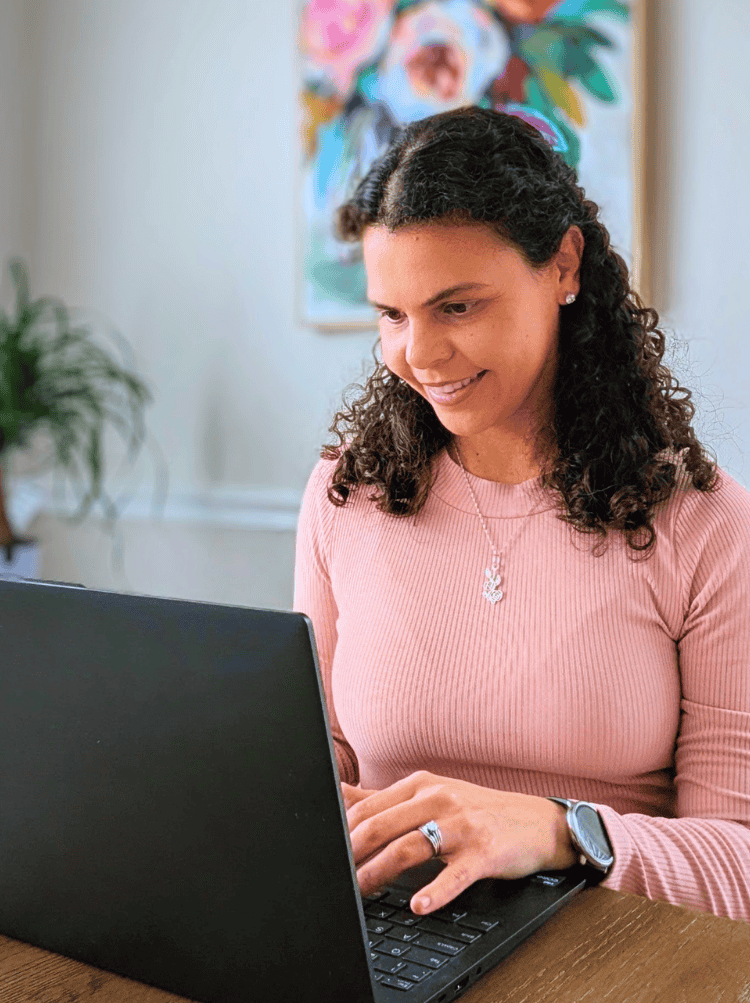 A woman at her desk with her laptop open, researching how to optimize linkedin profile for job search - Ana Goehner